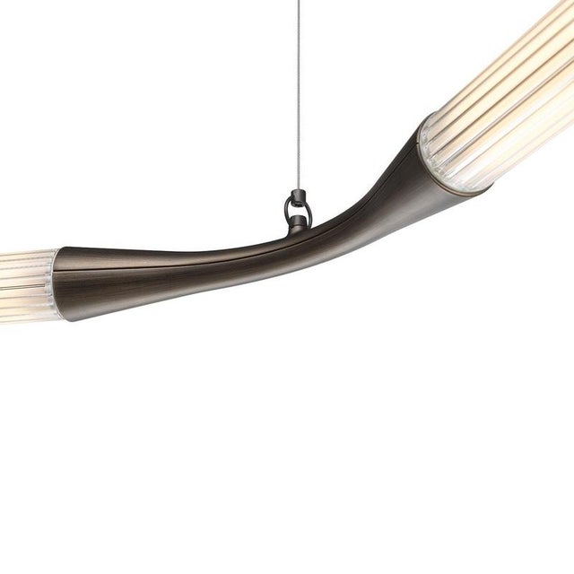 A sculptural suspension light by Lorenza Bozzoli, defined by a continuous C-shaped line that stretches horizontally with...