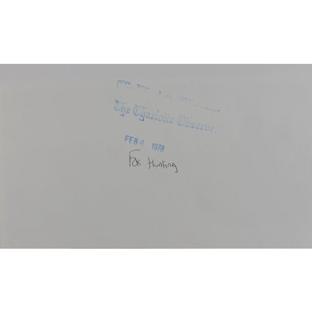 1983 black and white photograph of fox hunters on horses along a road in NC. Publication information on the back. Combined...