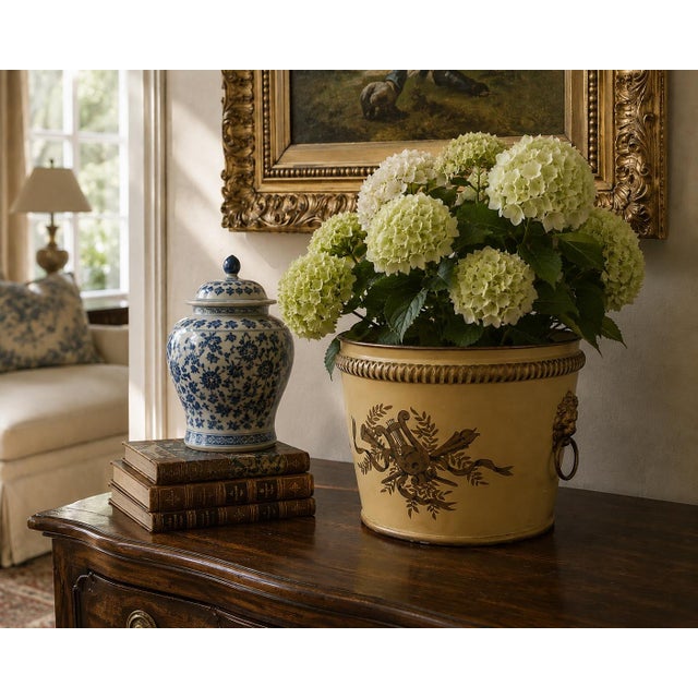 A distinctive early 20th-century tole cachepot painted in a warm, time-softened yellow and decorated with a hand-painted...