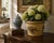 A distinctive early 20th-century tole cachepot painted in a warm, time-softened yellow and decorated with a hand-painted...