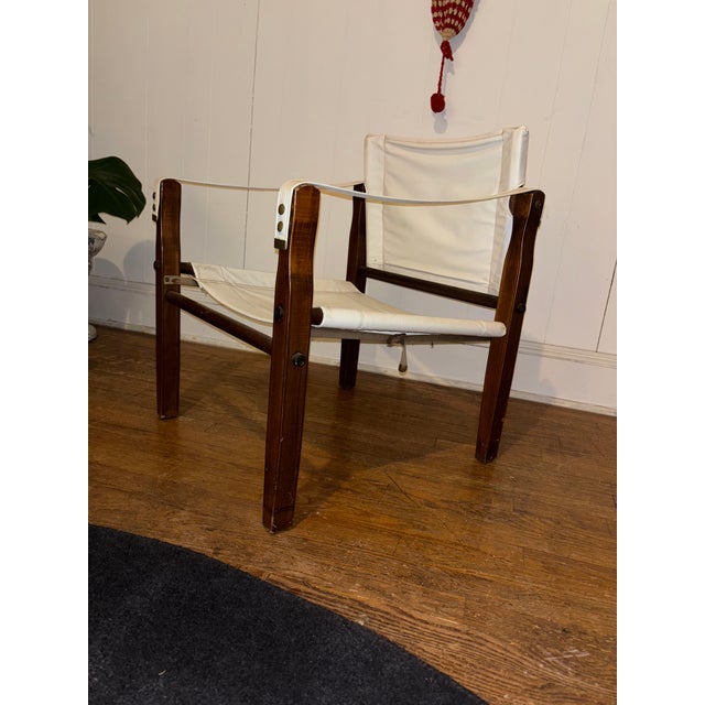 Vintage safari-style lounge chair featuring a solid wood frame with a suspended canvas sling seat and back. Inspired by...