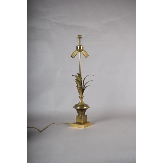 A striking brass table lamp with a sculptural palm / foliate motif, combining clean architectural lines with an elegant...