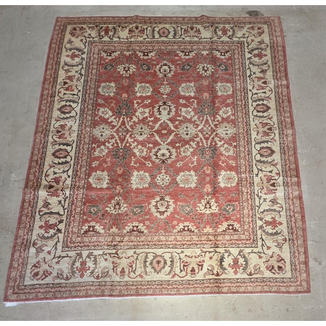 Vintage Oushak-style wool rug featuring a warm salmon field framed by a contrasting ivory border. The open floral...