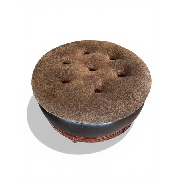 Round ottoman with a paisley pattern upholstered top and dark brown leather sides. Carved apron with rosettes above turned...