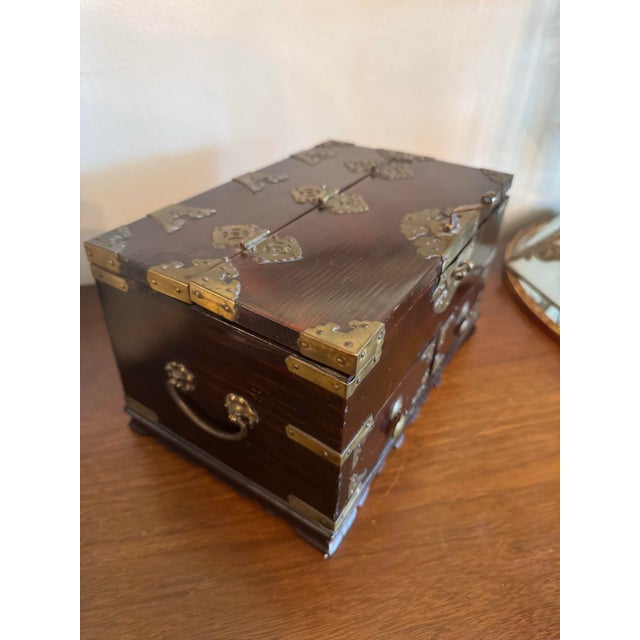 Vintage rare Chinoiserie lacquered wooden jewelry box adorned with Brass hinges and details. Has a dark lacquered stained...