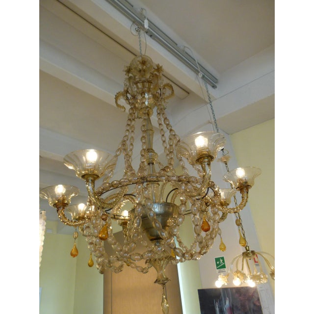 This vintage Italian eight-armed chandelier is made of amber blown glass. This piece is attributed to the mentioned...