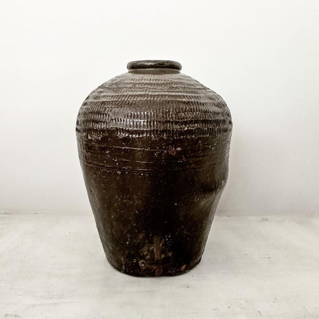 Heavy brown glazed antique water pots decorated with line patterns. Chinese brown glazed storage jars like these originate...