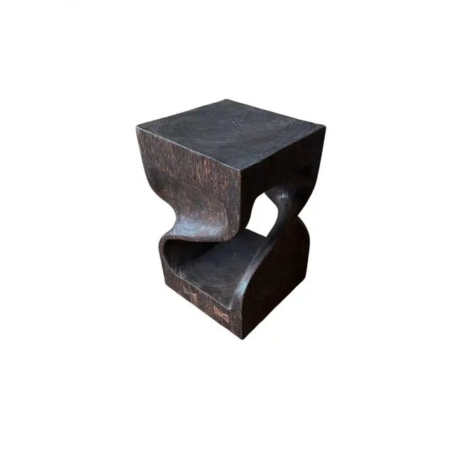 Hand-carved from solid suar wood, this striking side table features a fluid, sculptural form that blends organic curves...