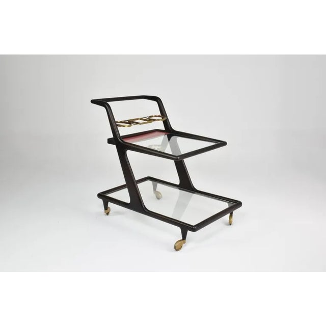 A beautiful 1950s Italian mid-century-modern serving cart designed with refined gold brass rollers. Its features two glass...
