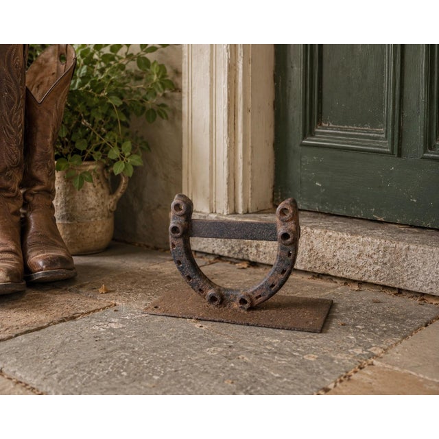 An early 20th-century American boot scraper constructed from a genuine iron horseshoe fitted with a straight scraping bar...