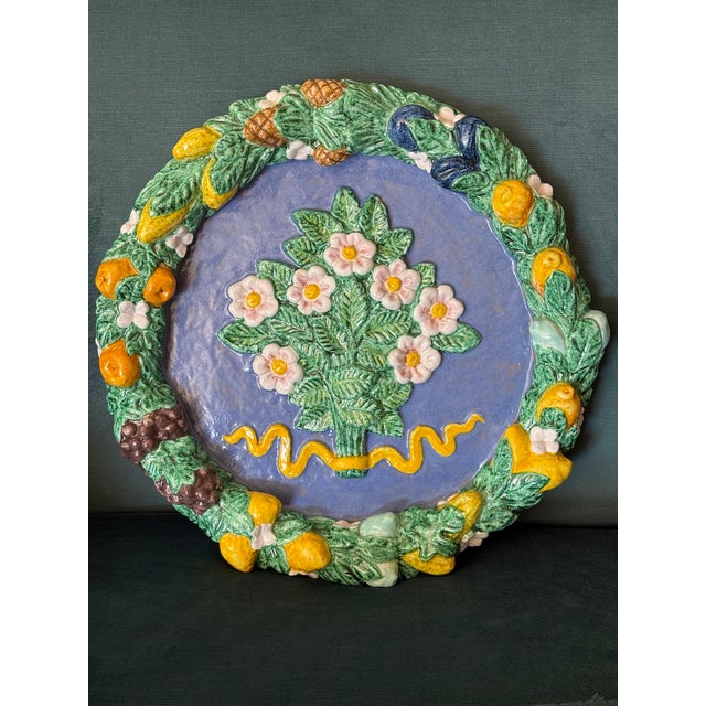 A large vintage Italian majolica wall charger in the Della Robbia revival style. The rim features a dense, raised garland...