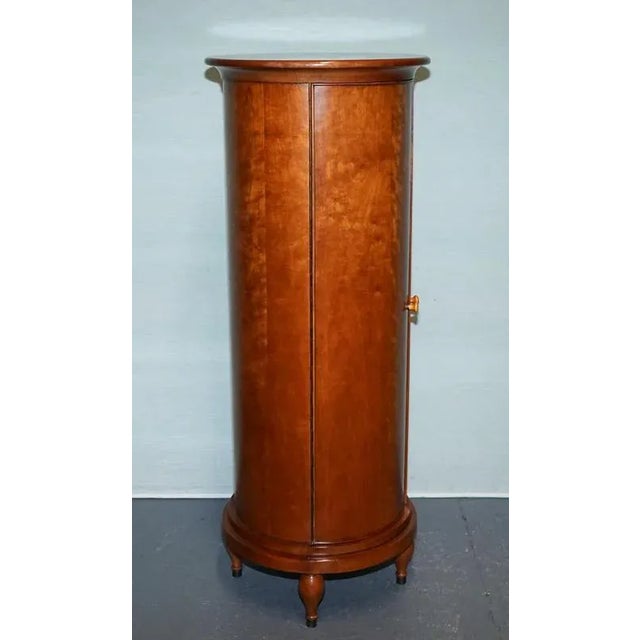 Antiques of London Presenting a refined mid‑20th‑century cylinder cabinet, executed in lustrous figured wood veneer and...