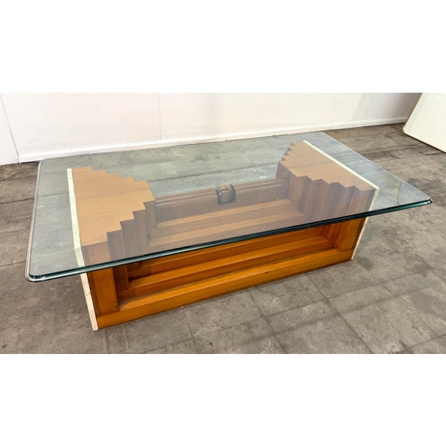 This Italian coffee table pairs a thick rectangular glass top with a sculptural wooden base, creating a composition that...
