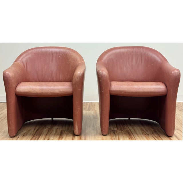 Vintage pair of petite modern armchairs in warm blush hue soft leather. Rounded back with curved arms and padded seat....