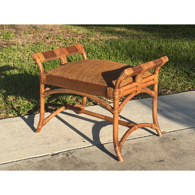 A charming vintage ottoman stool featuring a sculptural British Colonial-inspired frame with wrapped rattan joinery and an...