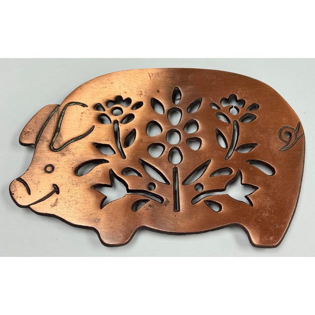 Vintage copper and cast iron pig motif trivet. Floral design to body. Hanging hardware on the back and rubber pads to the...
