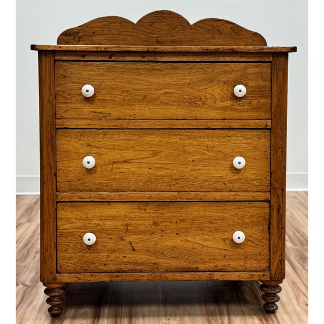 Antique pine three drawer chest featuring stunning patina, original porcelain knobs to dovetailed drawers, and scalloped...