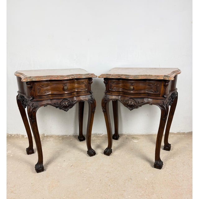 Elegant pair of French Louis XV-style nightstands crafted in wood, each featuring a shaped marble top, a serpentine...