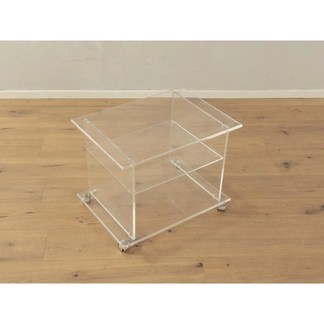 Wonderful side table from the 1960s. High-quality frame and shelf made of transparent acrylic with chrome-plated wheels....