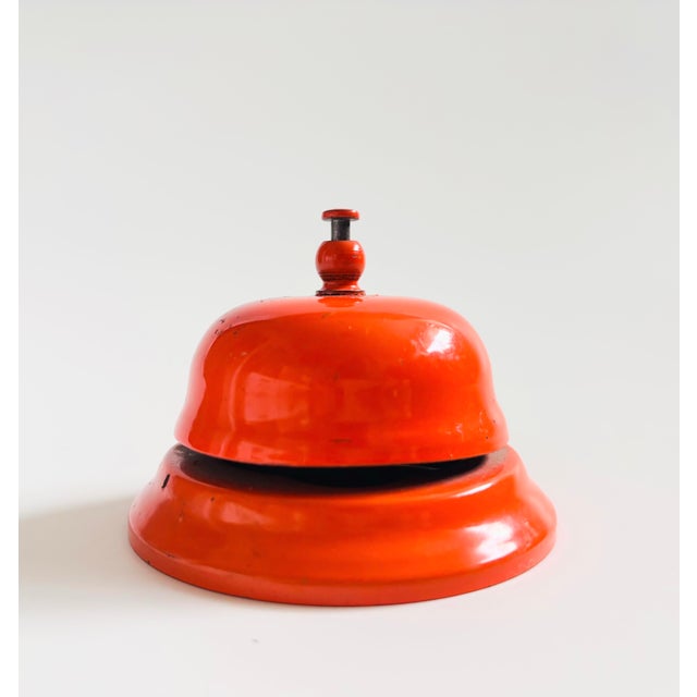 A vintage enameled metal hotel bell. Vibrant orange enameled finish. Working well.