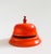A vintage enameled metal hotel bell. Vibrant orange enameled finish. Working well.