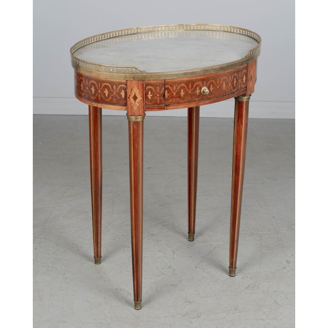A 19th century French Louis XVI style marble top marquetry oval side table, made of veneers of mahogany, walnut and...
