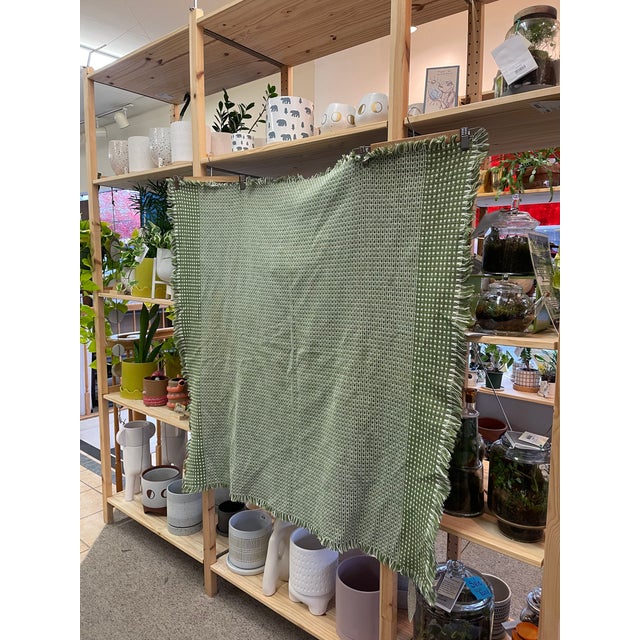 This vintage woven throw blanket features a charming geometric grid pattern in olive green and white,offering a timeless...