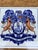 A classic Dutch Delft-style hand painted blue and white porcelain tile featuring an intricately rendered heraldic coat of...