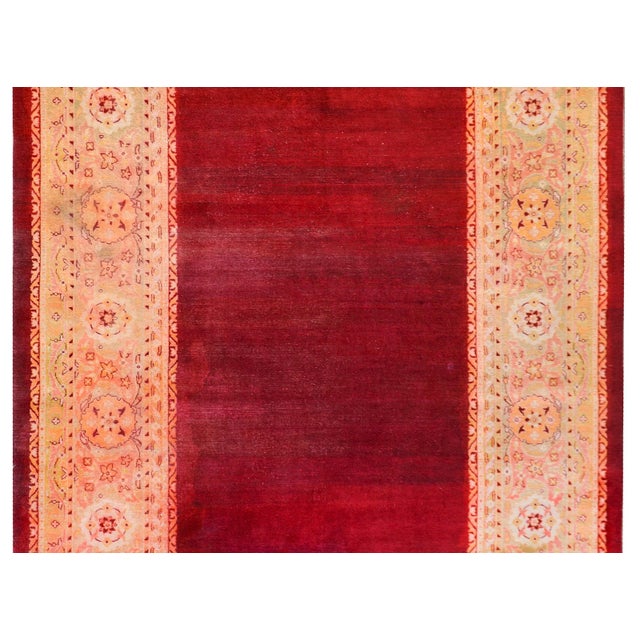 A beautiful early 20th century Indian Agra rug with an abrash crimson field surrounded by a wide floral pattered border...