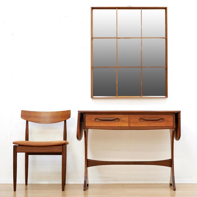 This mid-century wall mounted mirror was made in England during the 1970s by Rowley. Produced in teak, the frame is...