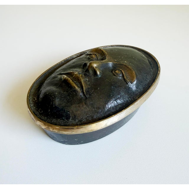 A small sculptural bronze box crafted by Nelles Studio, signed and dated 1989. It features an oval-shape with a serene...