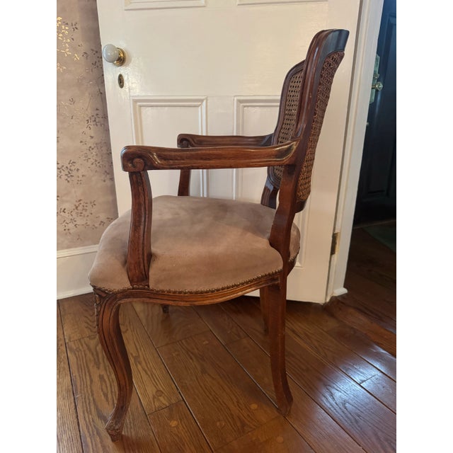 Charming petite carved wood arm chair with caning on both front and back. Styled after Louis XV. Suede seat has a few...