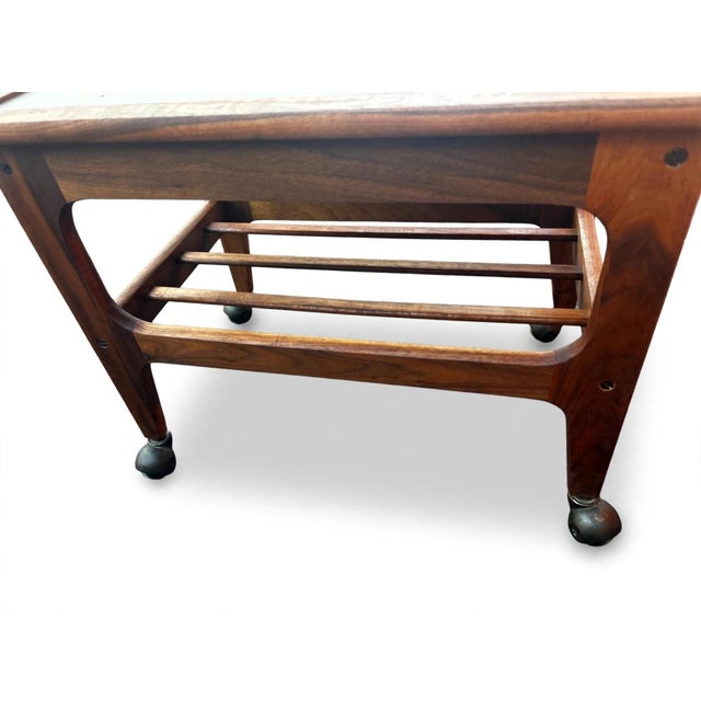 Vintage teak rolling cart has a rich brown wood grain finish. This piece is constructed with a solid wood frame and a...