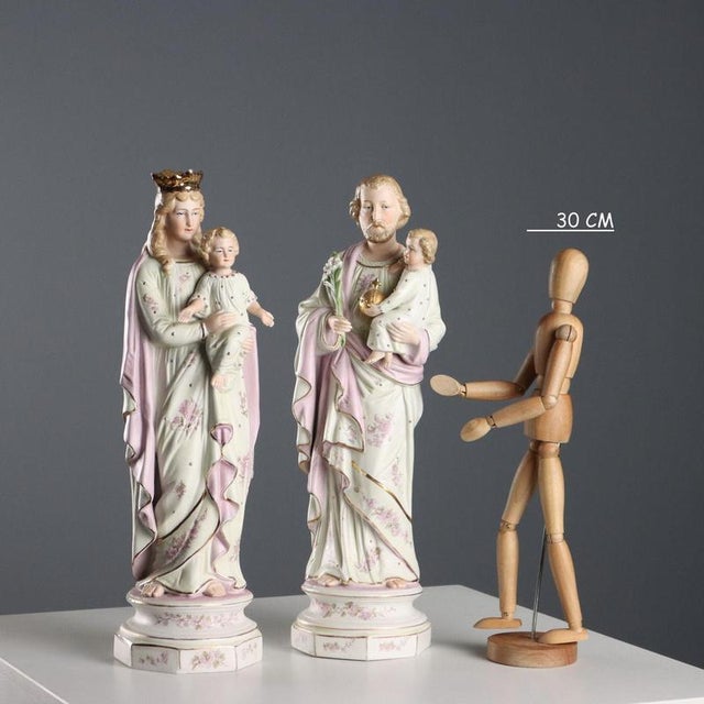 Pair of polychrome biscuit porcelain sculptures with gold details. The sculptures depict the Madonna and Saint Joseph with...