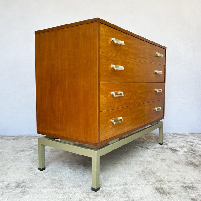 Afrormosia-veneered carcase construction on a painted metal stand base. Four full-width graduated drawers with dovetail...