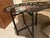 Vintage tôleware tray table, which features a hand-painted floral metal tray resting on a folding black faux-bamboo base....