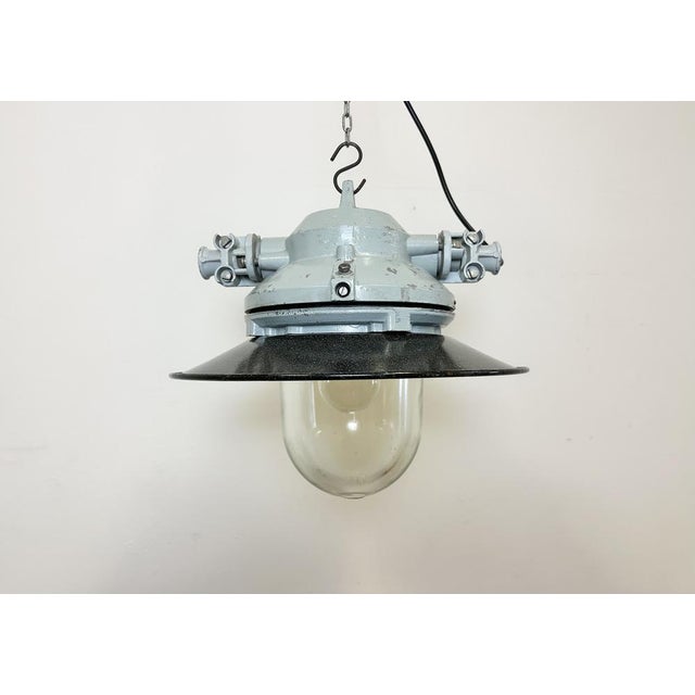 Grey industrial lamp with massive protective glass bulb made by Elektrosvit in former Czechoslovakia during the 1970s.It...