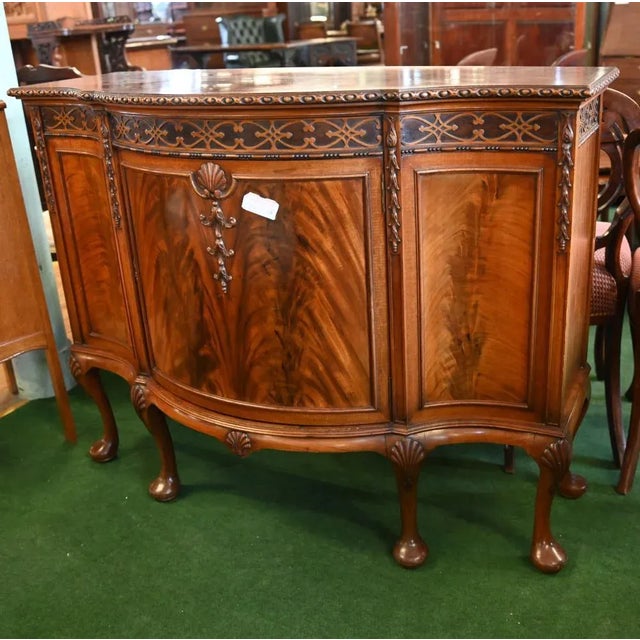 Elegant serpentine sideboard in the Chippendale manner with flame mahogany doors Terminating on Queen Anne legs with ball...