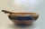 A large carved wooden bowl decorated with animals and mountains. Serving fork and spoon measure 12 inches long.