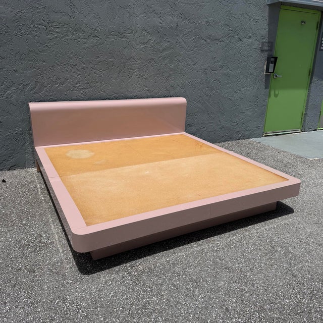 A striking postmodern king-size platform bed featuring a sculptural waterfall silhouette and glossy blush pink laminate...