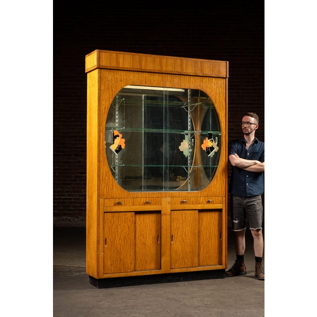 Monumental Art Deco display cabinet with mirrored back and reverse-painted figural glass. Built to impress, this full-...