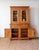 Substantial rustic pine stepback cupboard, featuring glass-front upper cabinet doors, paneled lower storage, and warm...