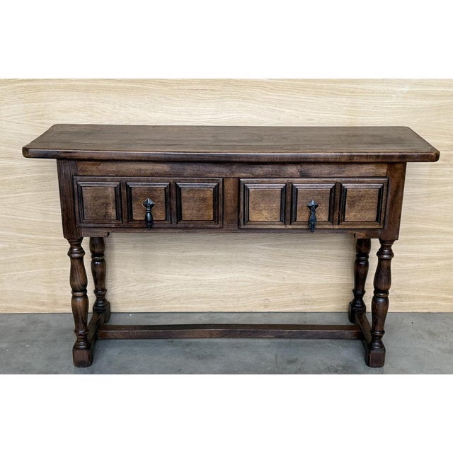 Spanish console table with two carved drawers, with iron handles that stand on four legs in the shape of domed columns and...