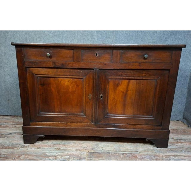 A Louis Philippe period low sideboard in solid walnut, dating from the 19th century. This piece features a simple and...