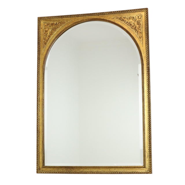 Vintage gold-tone Deknudt mirror featuring beveled glass and a classic style; adorned with floral motifs at the top left...