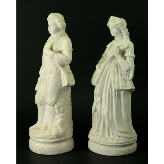 a nice pair of large bisque figurines White Parian porcelain depicting a man and a woman in Rococo-style attire Both are...