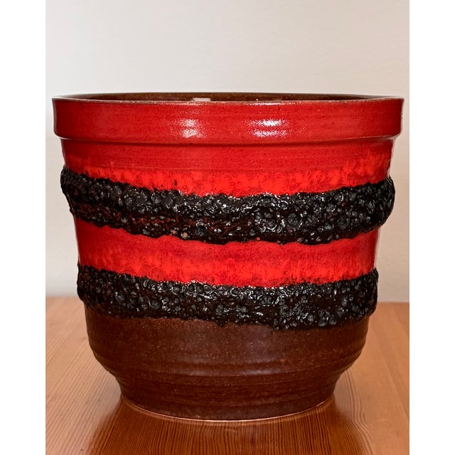 A substantial vintage West German Bay Keramik ceramic planter featuring vivid red glaze, deeply textured black lava-glaze...