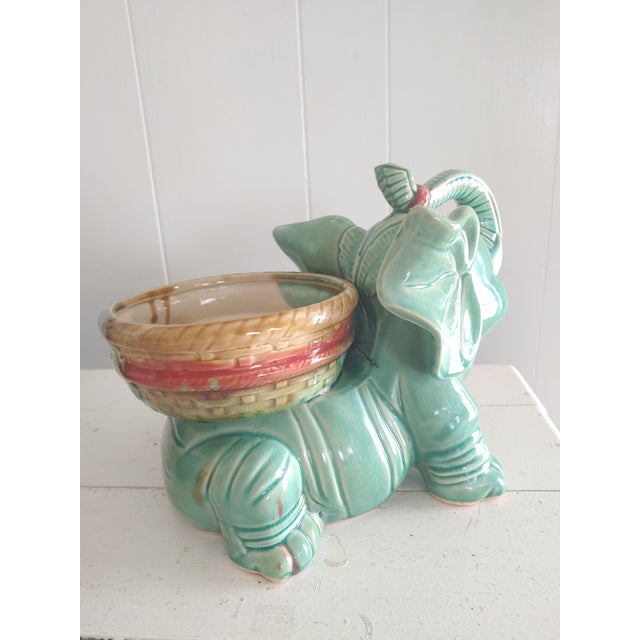 Here's an adorable planter stand featuring an elephant, trunk up. Majolica glaze and tropical accents create a whimsical...