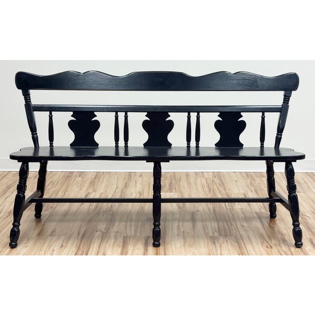 Vintage Early American black wood bench featuring a multi-splat spindle back with turned legs and a distressed black...