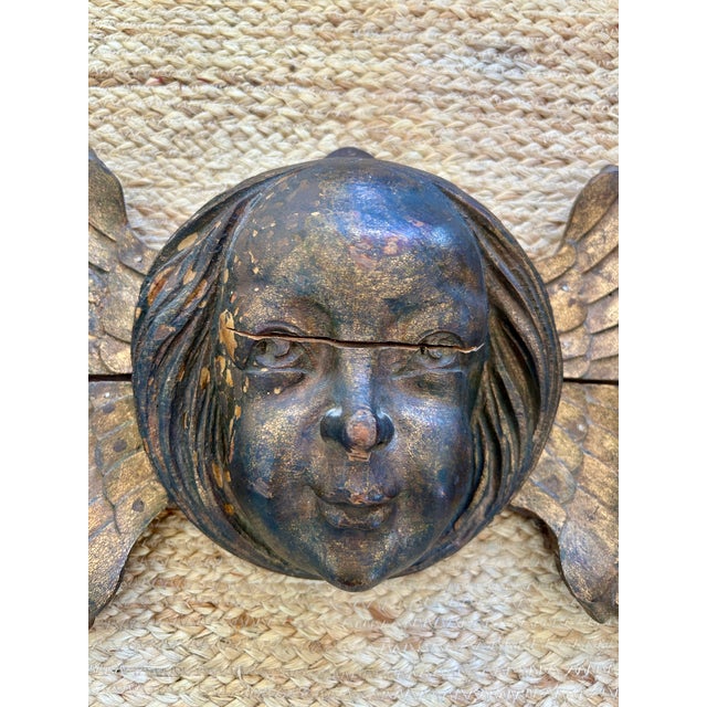 A striking antique - late 19th - early 20th Century angel over door wall appliqué featuring a serene cherub head flanked...